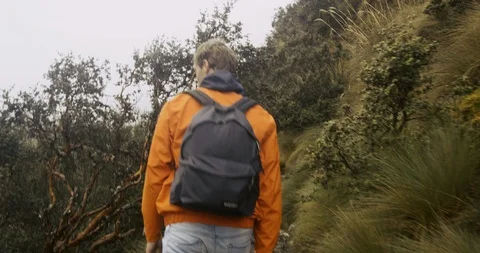 Young man walking on muddy path in grassland mountains with big lake Stock Footage 87212908