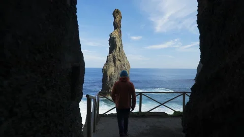 Young man walking out of dark cave towards the ocean Stock Footage 146632803