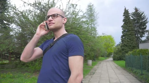 Young man walking in the park and talking on the phone. Stock Footage 62520158