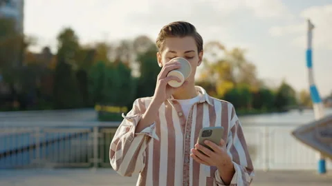 Young Man Walking in Park Using Smartphone, Texting With Friends. Holding Phone Stock Footage 237593875