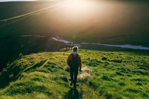 Young man walking on a path towards Durdle Door alongside Jurassic Coast Stock Photos