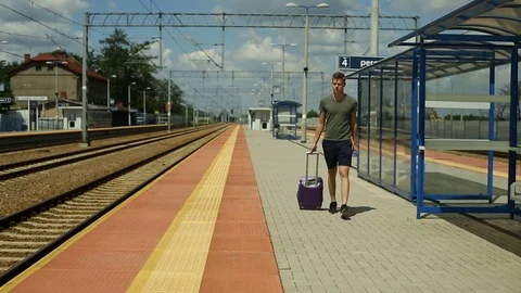 Young man walking on the platform with the luggage and checking time on phone Stock Footage 78656252