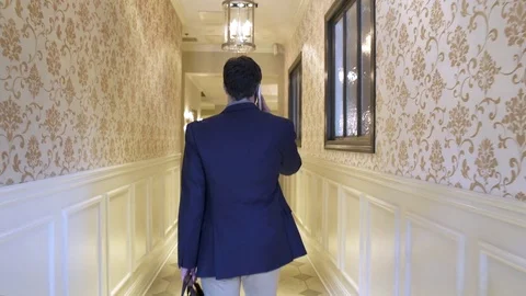 Young man walking up to a reception desk of a hotel 動画素材 77094779