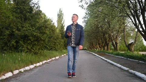 Young man walking on the road and listening music Stock Footage 130129985