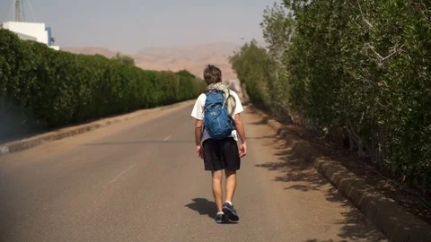 Young man walking by the road with backpack slow motion Stock Footage 74251343