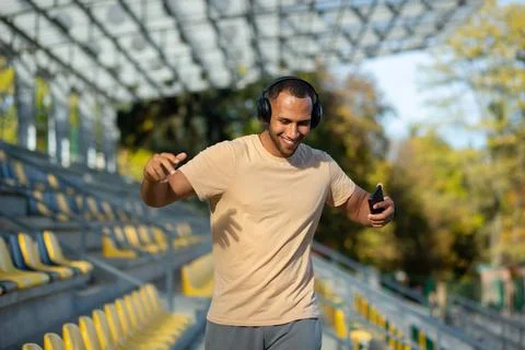Young man walking in stadium after exercise and jogging in headphones, listening Fotos de archivo