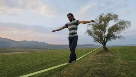 Young man walking steadily on slackline Stock Footage 121868516
