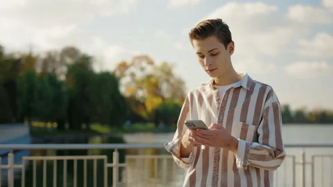 Young Man Walking on the Street Using his Smartphone, Texting With Friends Stock Footage 237009558