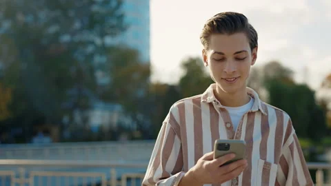 Young Man Walking on the Street Using His Smartphone, Texting with Friends Stock Footage 240228432