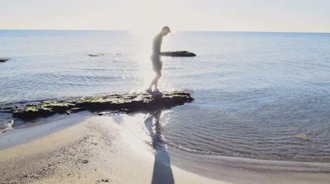 Young man walking in the sun light on the beach slow motion Stock Footage 57296082