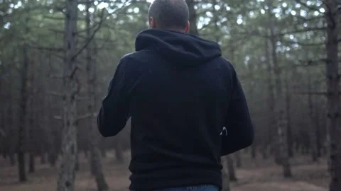Young Man Walking Through The Forest In A Black Hoodie. 4k Slow Motion Stock Footage 180397810