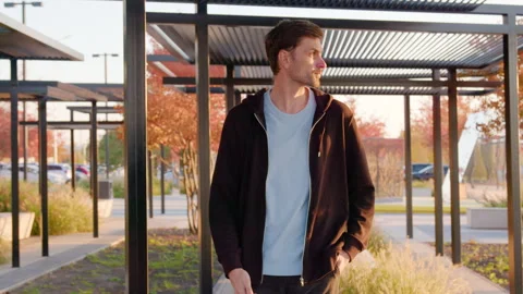 Young man walking through a modern outdoor park with stylish architecture Stock Footage 316835537