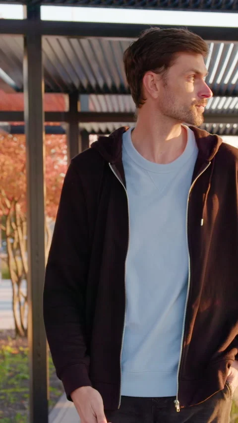Young man walking through a modern outdoor park with stylish architecture Stock Footage 318472927