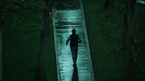 Young man walking through the park in rainy weather Video stock 306311750