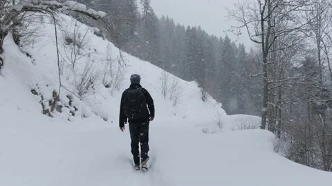 Young man walking through snow during heavy snowfall Stock Footage 231549602