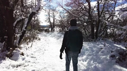 Young Man Walking Through Snowy Winter Landscape on a Scenic Forest Path Vídeo Stock 338219606