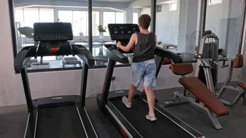 Young man walking on treadmill in modern gym with fitness equipment. Stock Footage 343879028