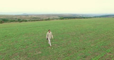 Young Man Walking Trough the Field Aerial Stock Footage 56114892