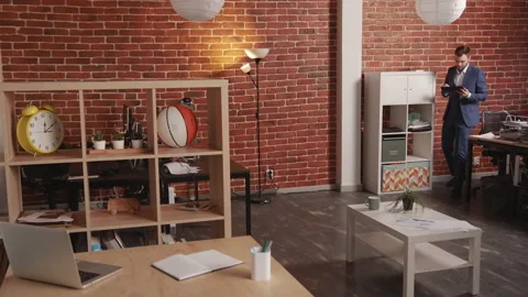 A young man walks across an empty office and types into a computer tablet Stockbeeldmateriaal 194363825