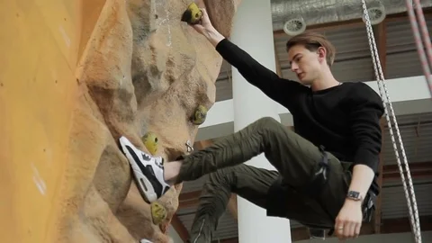 Young man walks along down on climbing wall in sports club. Stock Footage 83149678