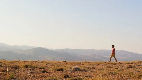 Young man walks along a path against the backdrop of mountains. Stock Footage 276484643