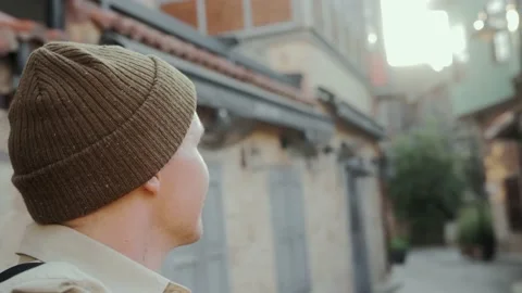 Young man walks at dawn through the beautiful old streets in front of the camera Stock Footage 220850802