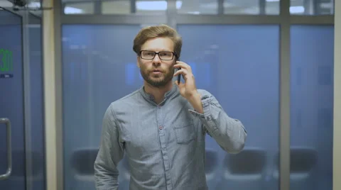 Young man walks down the hallway and talking on the phone Stock Footage 68612933