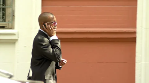A young man walks down the street while talking on his cell phone Stock Footage 34000447