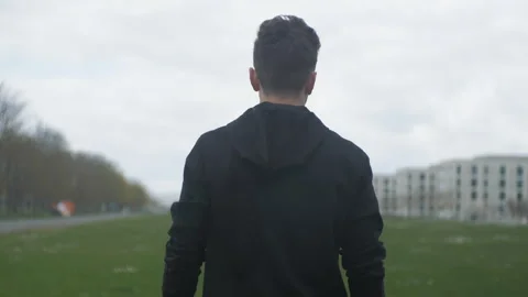 A young man walks forward in the rain. Moving forward. Motivation Stock Footage 272170878