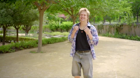 A young man walks a path, texting on his smartphone, immersed in tech and nature Stock Footage 281609056
