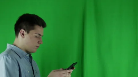 Young man walks in with phone shrugs and leaves in front of greenscreen Vidéo 59087610