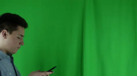 Young man walks in with phone waves off and leaves in front of greenscreen Vidéo 59087377