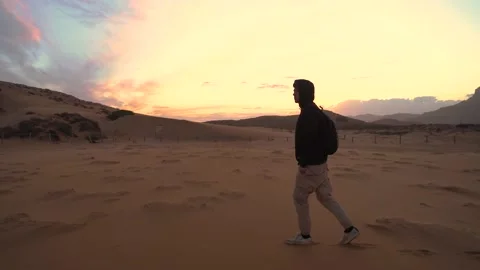 Young man walks through the dunes of a beach with virgin sand in a natural se Stock Footage 218255016