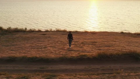 A young man walks towards the summer sunset. Aerial view of a colorful sunset Stock Footage 160120976