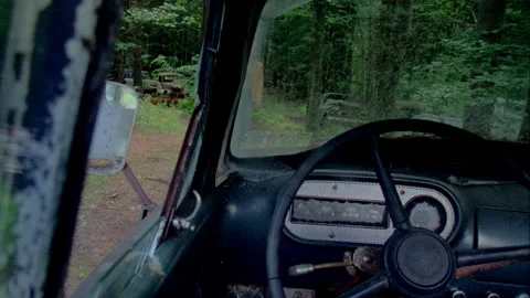 A young man walks uo to an old truck in a junkyard and sees the dashboard Stock Footage 272267558