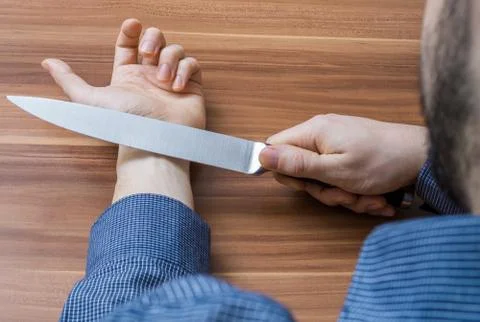 Young man wants to commit suicide by cutting vein on hand with knife. Stock Photos