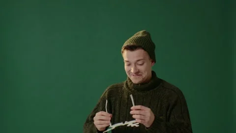 A young man in a warm sweater, a cap and carnival glasses isolated on green. Stock-Footage 226219459