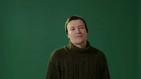 A young man in a warm sweater, a cap and carnival glasses isolated on green. Video stock 226219608