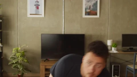Young man warming up before exercising at home in living room Stock Footage 169015032