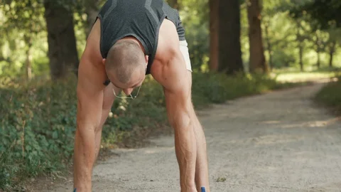 Young man warming up before jogging in park Stock Footage 92850109
