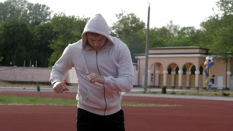 Young man warms up before jogging in park Stock Footage 130138488