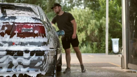 A young man washes a car in a blue glove with a foam sponge.car wash Stock Footage 197574096