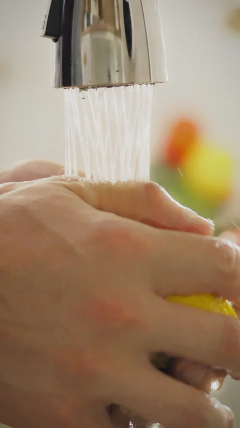 Young man washes fresh lemon under running water in a home kitchen Stock Footage 331742357