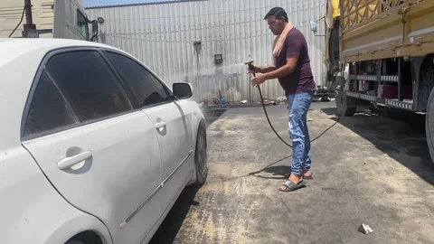 Young man washes his car at a self-service car wash Vidéo 276774059
