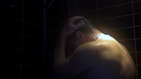 Young man washes his head in the shower Stock Footage 100710990