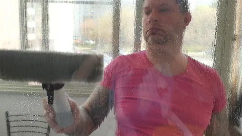 A young man washes the windows of his house. Spring cleaning. Stock Footage 128966254