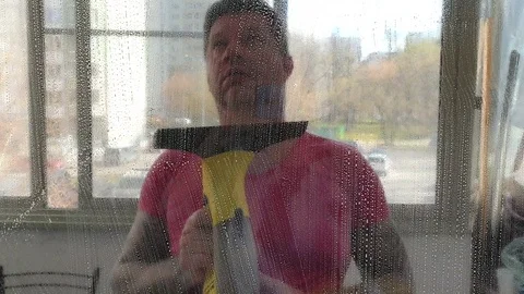 A young man washes the windows of his house. Spring cleaning. Stock-Footage 128966258