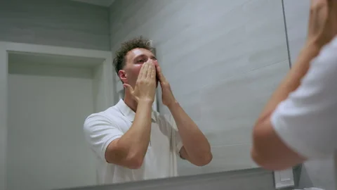 Young Man Washing His Face in Bathroom Mirror Reflection 库存影片 340106271