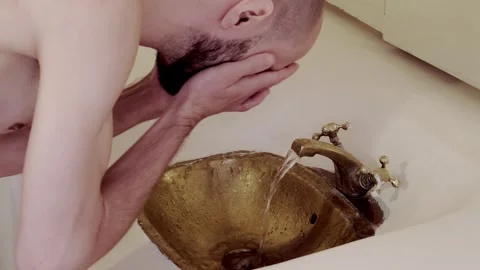 Young man washing in Rustic brass sink, morning skincare routine in Morocca.. Stock Footage 304466387