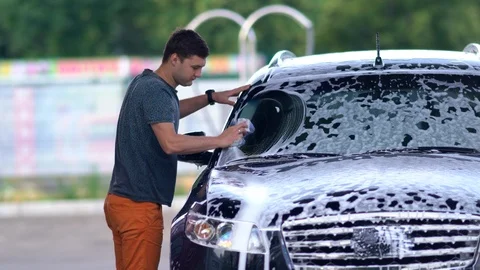 Young man washing the windscreen on his car Stock Footage 110814641